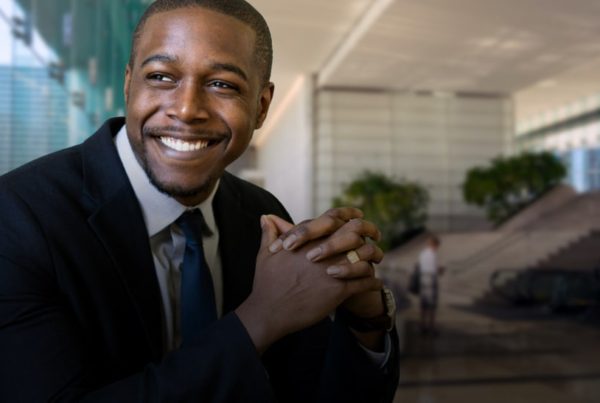 Gentleman officially dressed smiling while looking through the window in an office