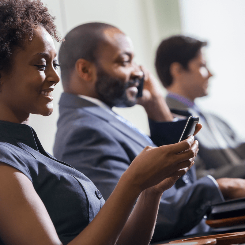 Three people seated in an office while on their phones
