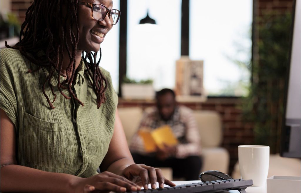 Lady in the living room all smiles while working, typing on her keyboard | Madison Life Insurance