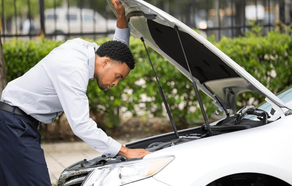 A gentleman looking at his engine on the highway - Madison Motor insurance