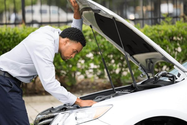 A gentleman looking at his engine on the highway - Madison Motor insurance