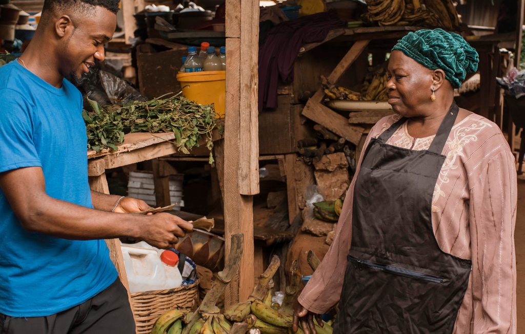 African accent Gentleman paying for vegetables in the open air market
