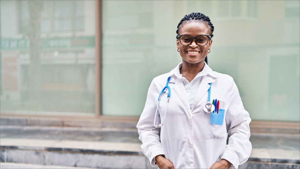 Beautiful African descent Clinical officer all smiles outdoors with stethoscope and lab coat on | Madison Professional Indemnity Cover