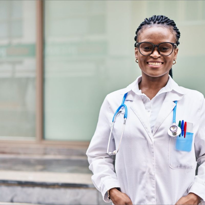 Beautiful African descent Clinical officer all smiles outdoors with stethoscope and lab coat on | Madison Professional Indemnity Cover